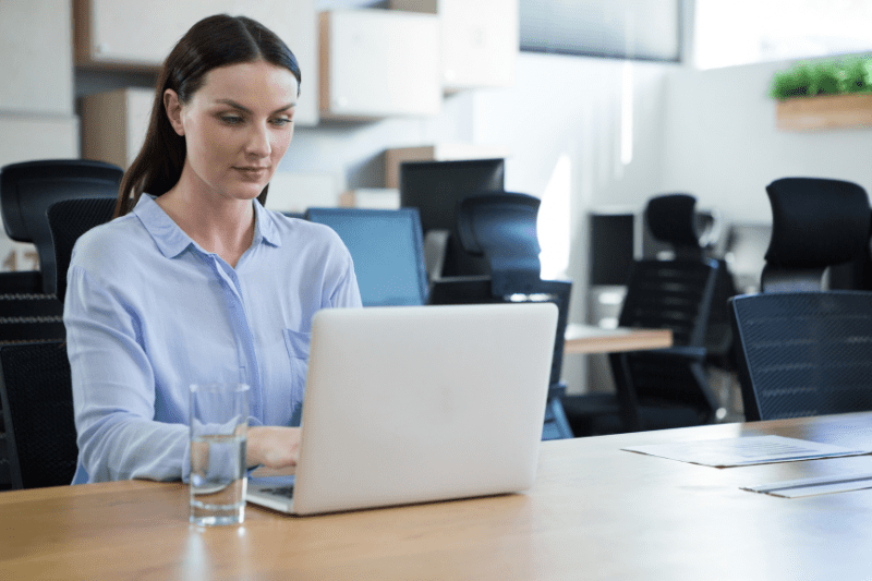 lead qualification: image of a woman in the office typing on a silver notebook