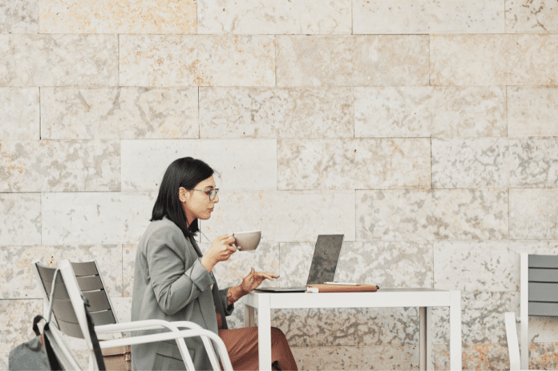 facebook business: imagem de uma mulher sentada, usando óculos, segurando uma xícara, olhando para a tela de um notebook