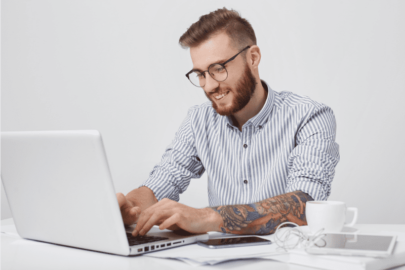 uplify: image of a man wearing a dress shirt and glasses, typing on a laptop typing