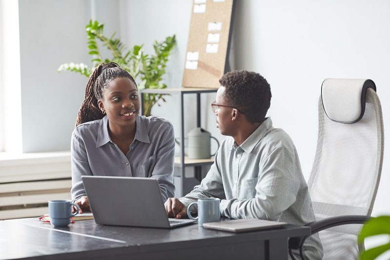 tráego pago x tráfego orgânico: dois colegas de trabalho no escritório com uma mesa e um computadoImagem de dois colegas de trabalho no escritório sentados em frente a uma mesa e um computador