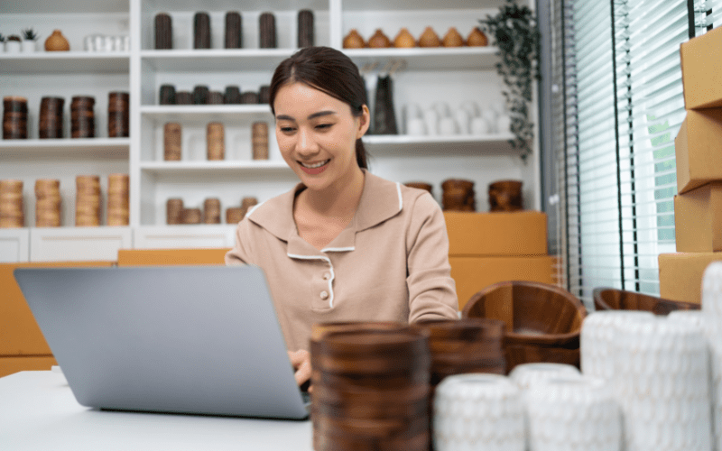 google merchant center header: imagem de uma mulher jovem asiática digitando no notebook com várias caixas de encomendas ao lado