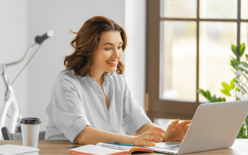 Google Analytics 4: image of a woman in a blue shirt, sitting down, typing on a gray notebook.