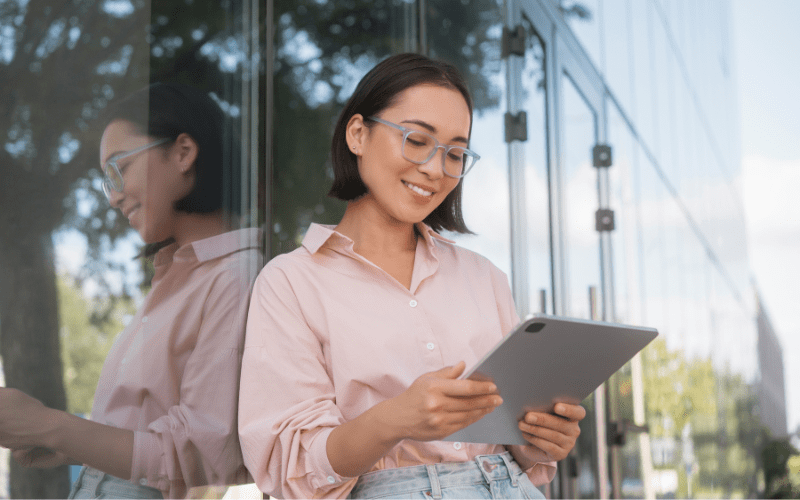 Marketing automation: woman standing, in a pink shirt, looking at an IPad
