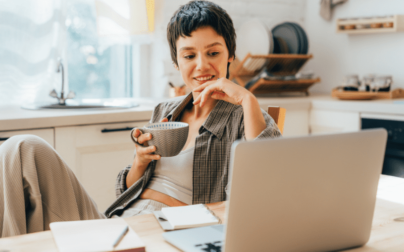Crear vídeos: mujer con pelo corto, sentada frente al ordenador, con una taza de té en la mano
