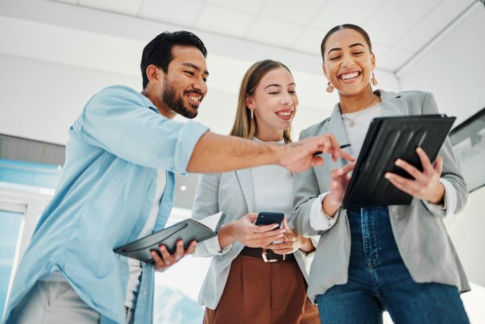 Exemplos de Inteligência Artificial: funcionários de marketing olhando para o Ipad e sorrindo. 