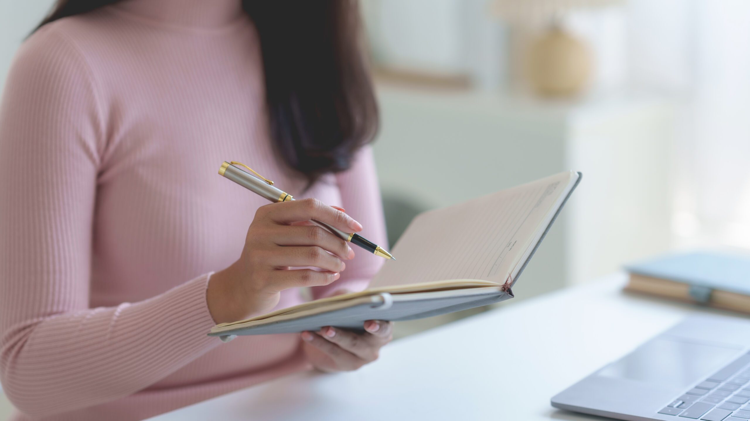 Engenharia de Prompt: mulher com uma blusa rosa, escrevendo no seu bloco de notas