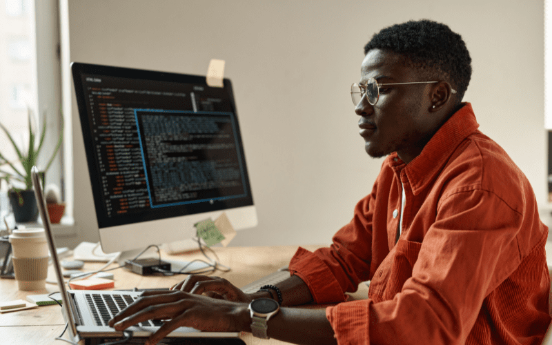 Prueba de Turing: imagen de un hombre negro con camisa naranja, mirando los códigos de su ordenador