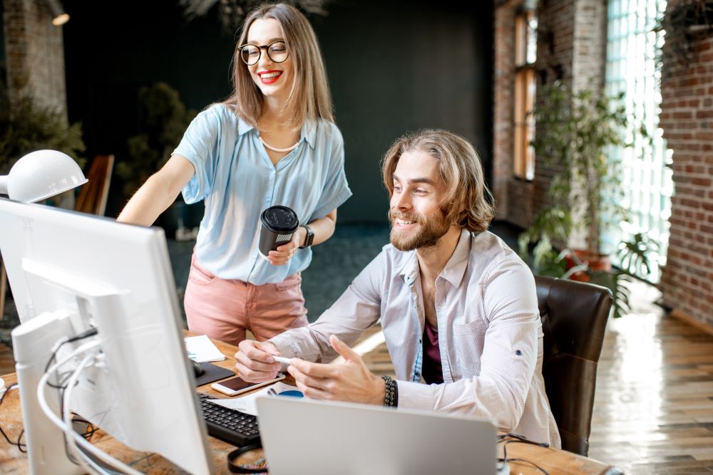 Inteligência Geral Artificial: casal sorrindo olhando para a tela do computador em um ambiente corporativo