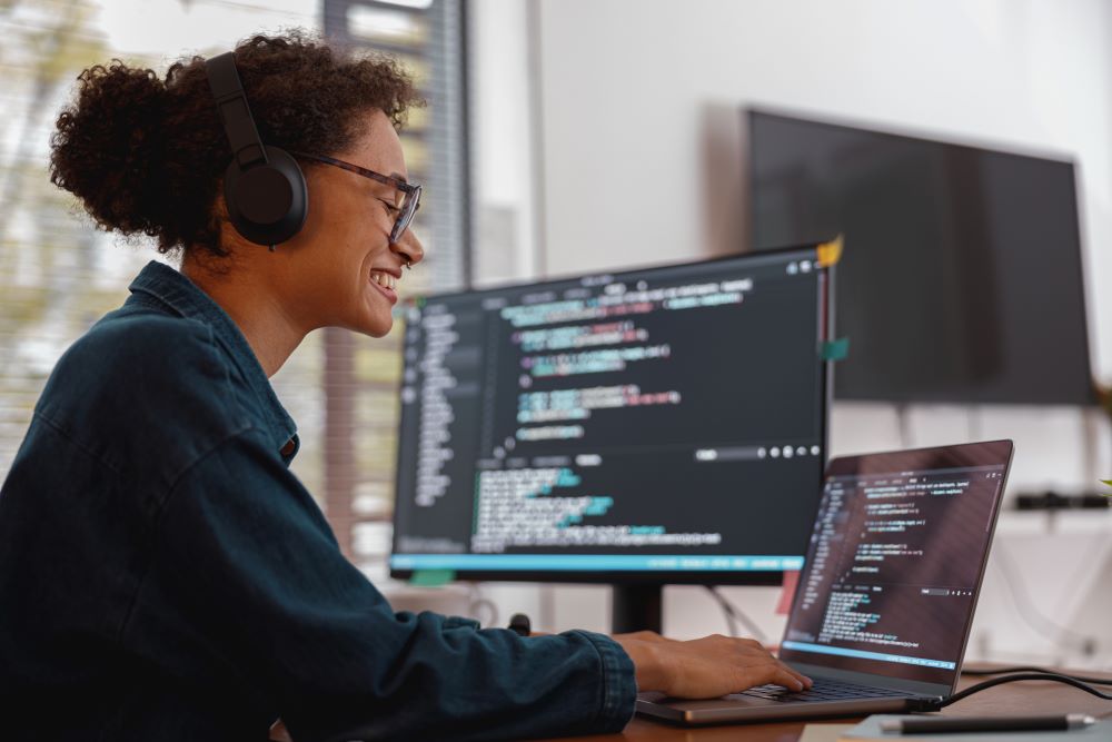 Data and AI: smiling black female software developer working on her computer.